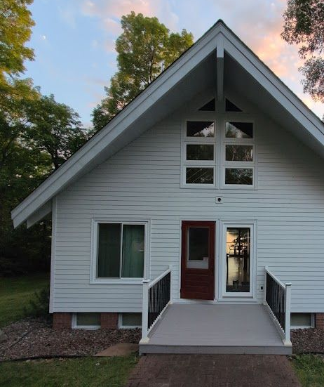 A front view of a tan, one-story house under renovation with construction debris and supplies on the lawn and porch.