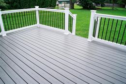 Gray composite deck with white railing and black spindles overlooking a green lawn.