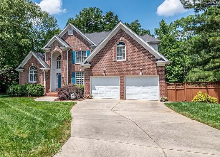 A large brick house with two garage doors and a driveway