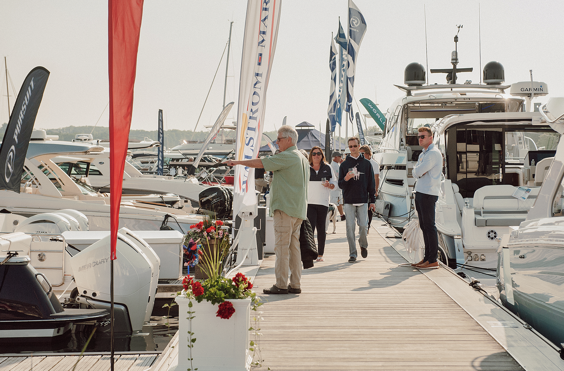 A group of people are standing on a dock next to boats.
