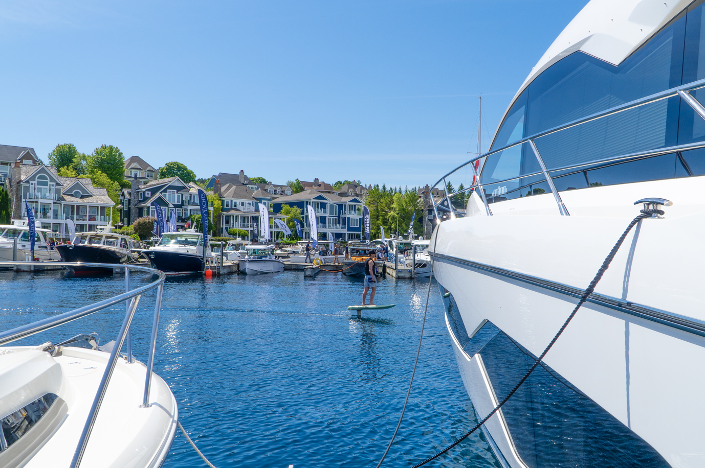 A boat is docked in a marina with houses in the background.