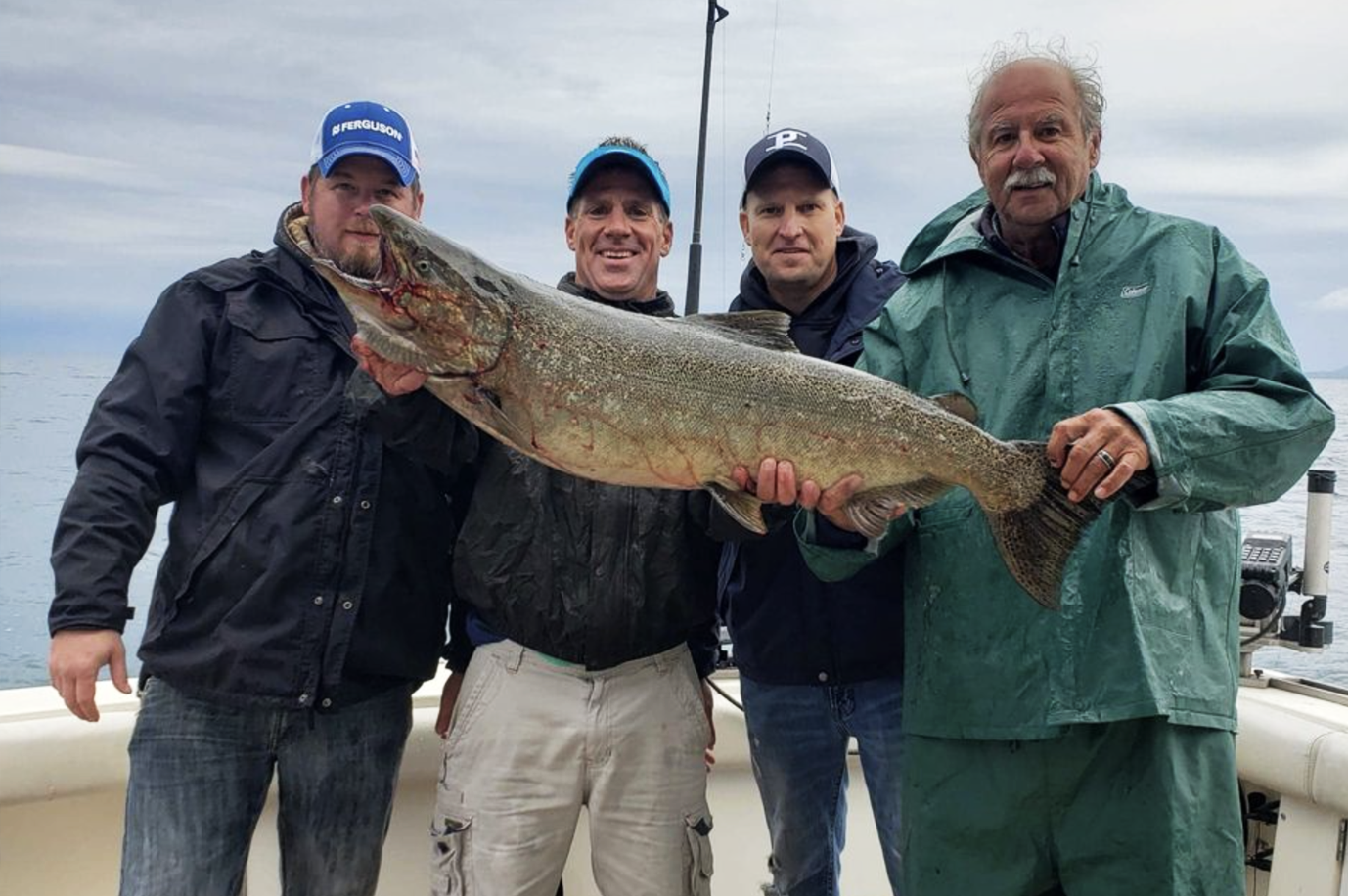 A group of men are holding a large fish on a boat.
