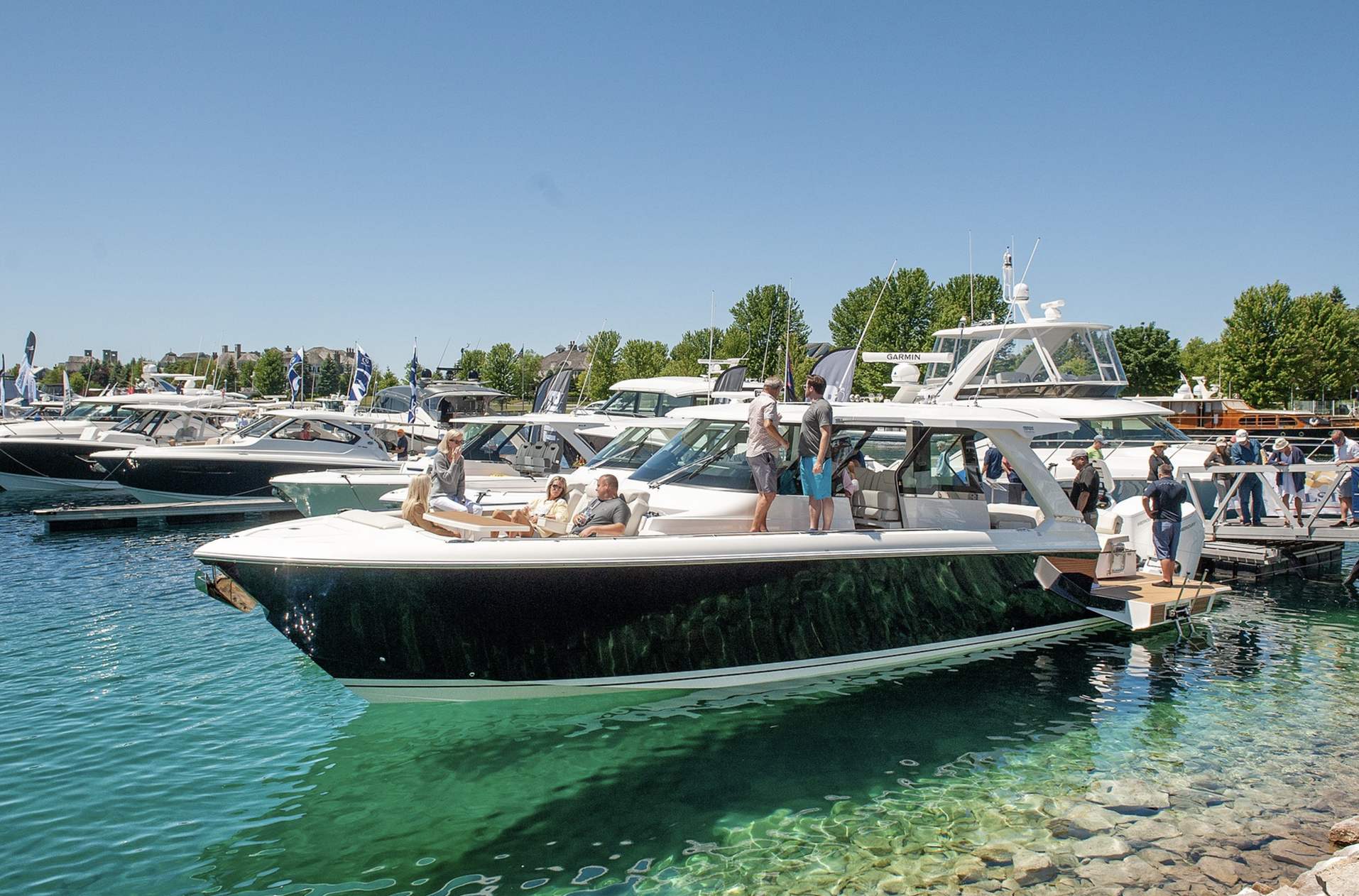 A row of boats are docked in a marina on a sunny day