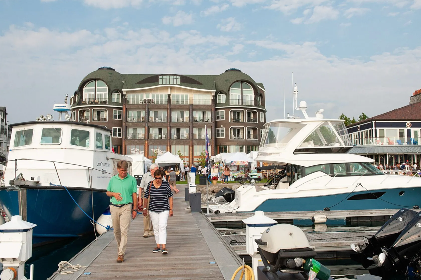 A man and a woman are walking down a dock next to boats.