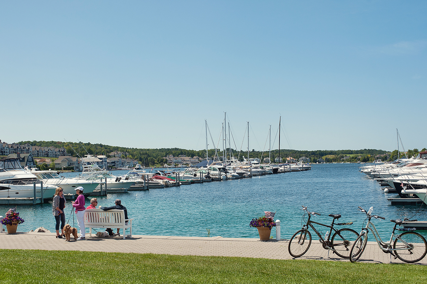 A group of people are sitting on a bench next to a body of water.