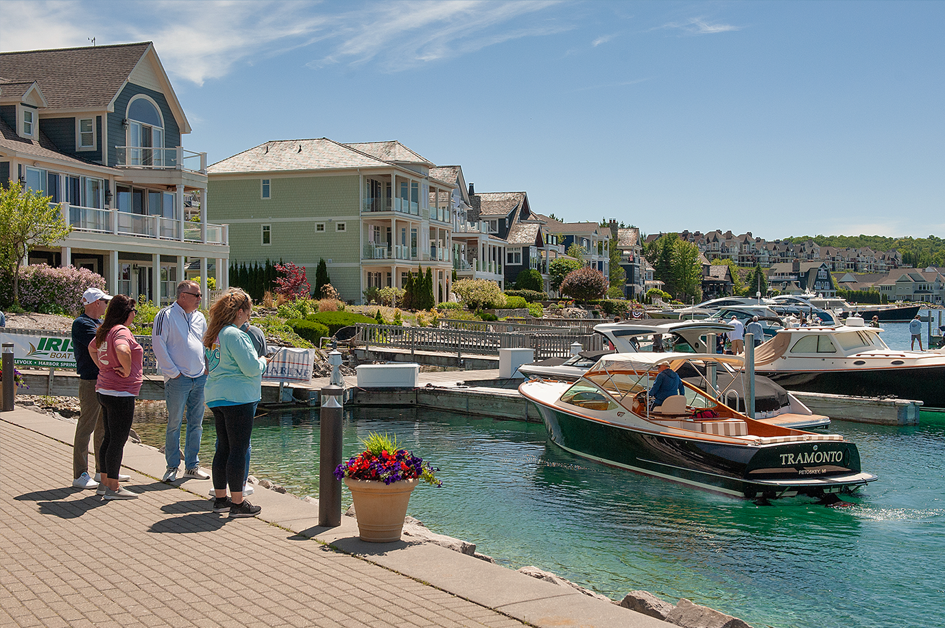 A group of people are standing on a dock looking at a boat in the water.