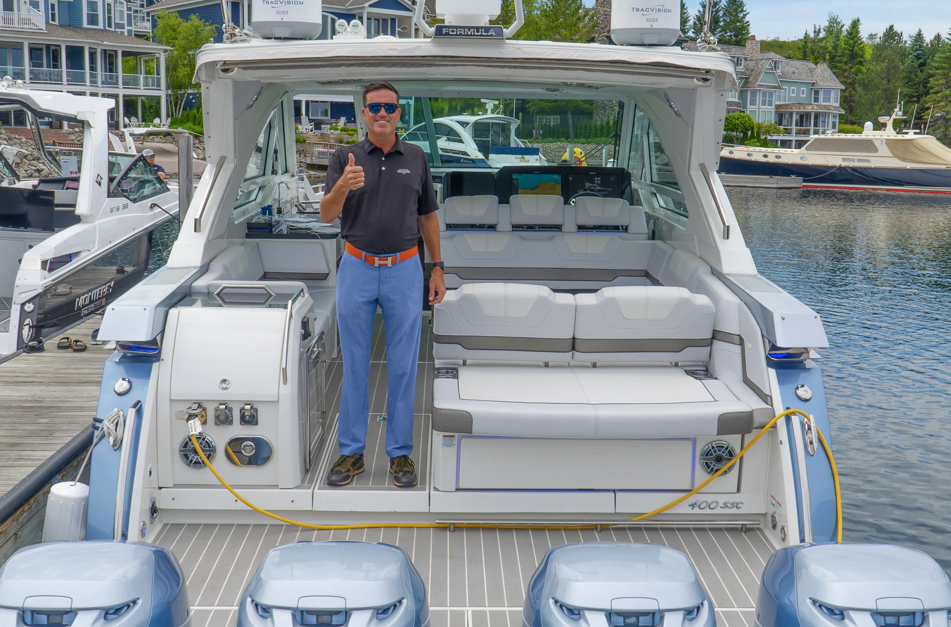 A man is standing on the back of a boat giving a thumbs up.