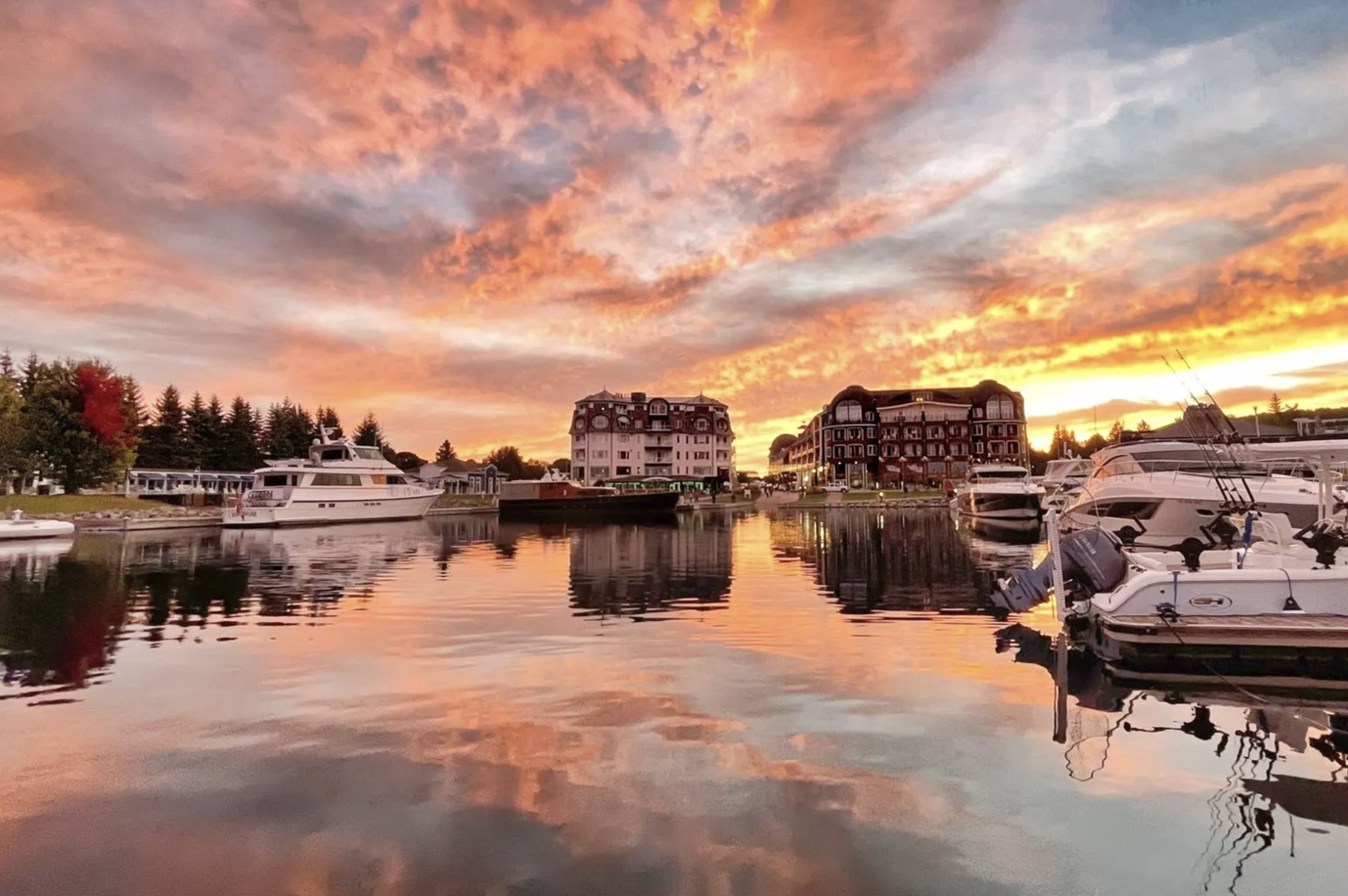A group of boats are docked in a harbor at sunset.