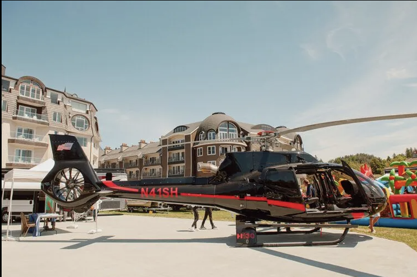 A black and red helicopter is parked in front of a building.
