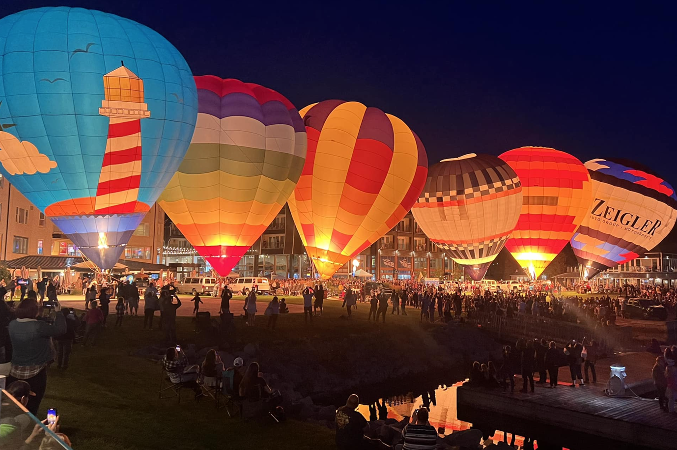 A bunch of hot air balloons are lit up at night