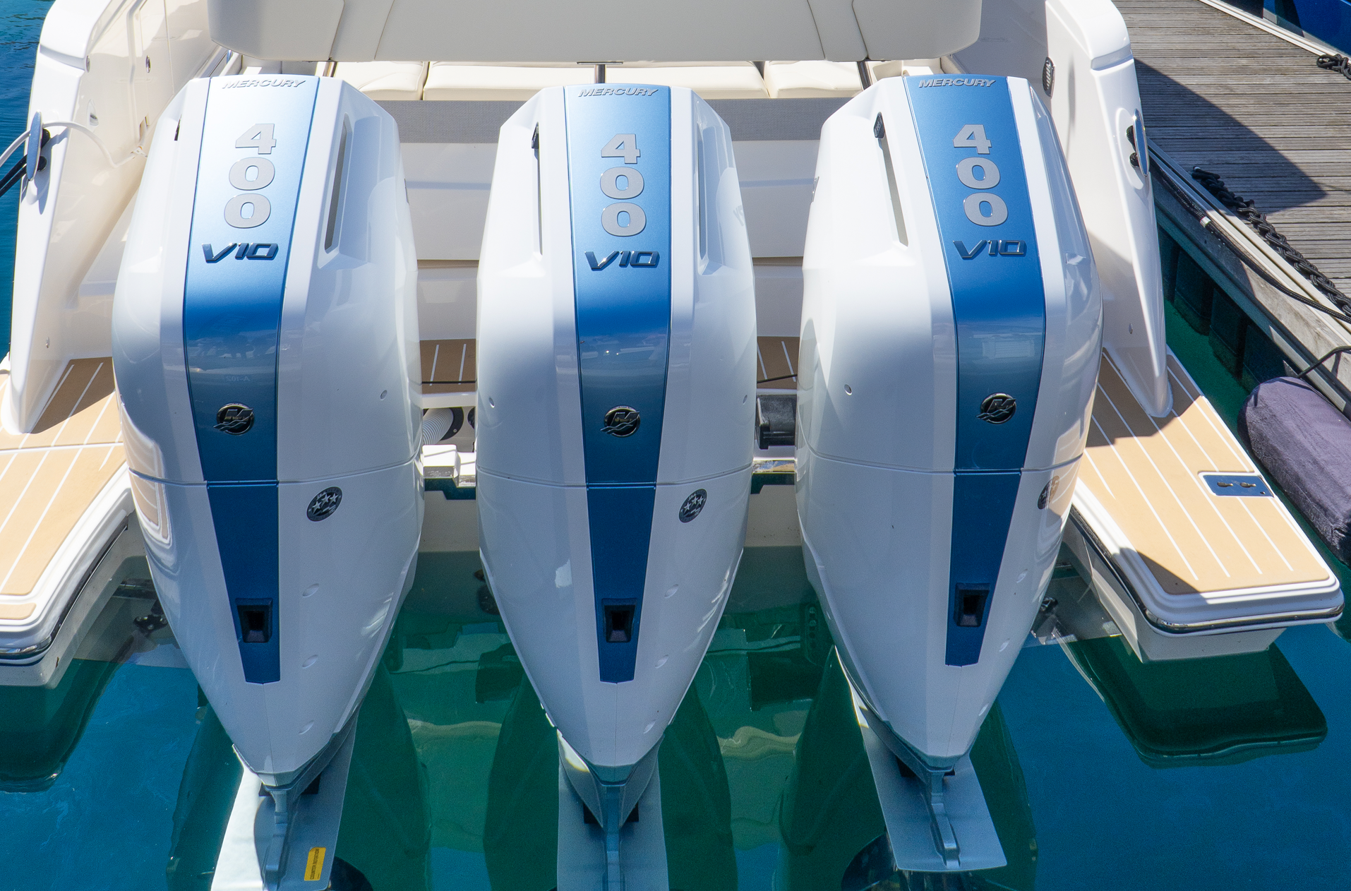 Three outboard motors are sitting on the back of a boat.