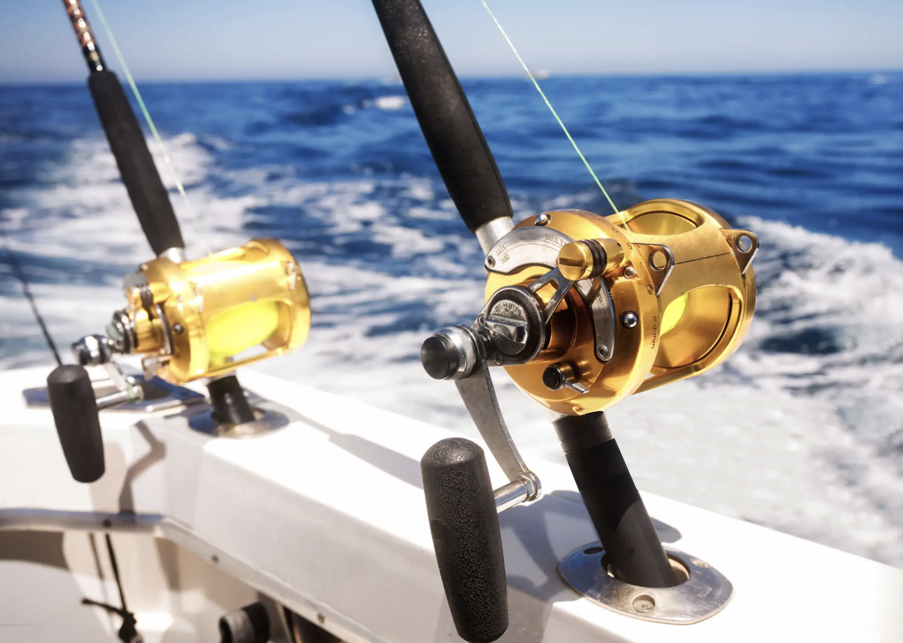 Two fishing rods are on a boat in the ocean.