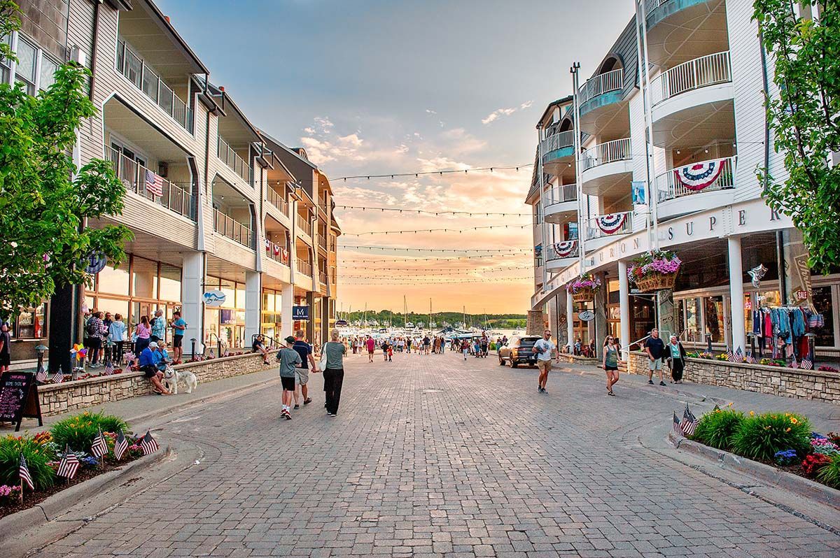 A group of people are walking down a cobblestone street between two buildings.