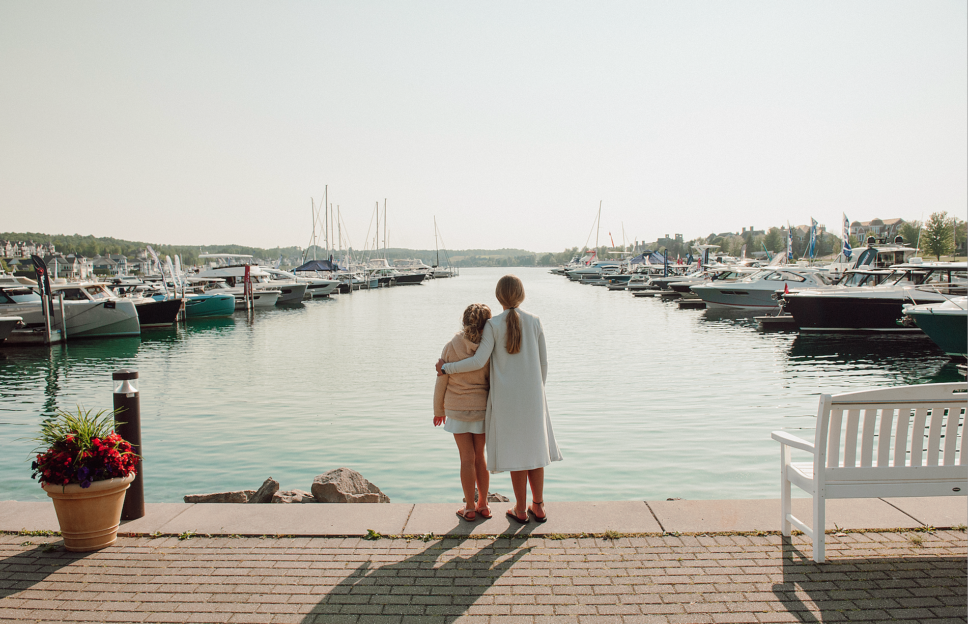 A woman and a child are standing on a dock looking at the water.