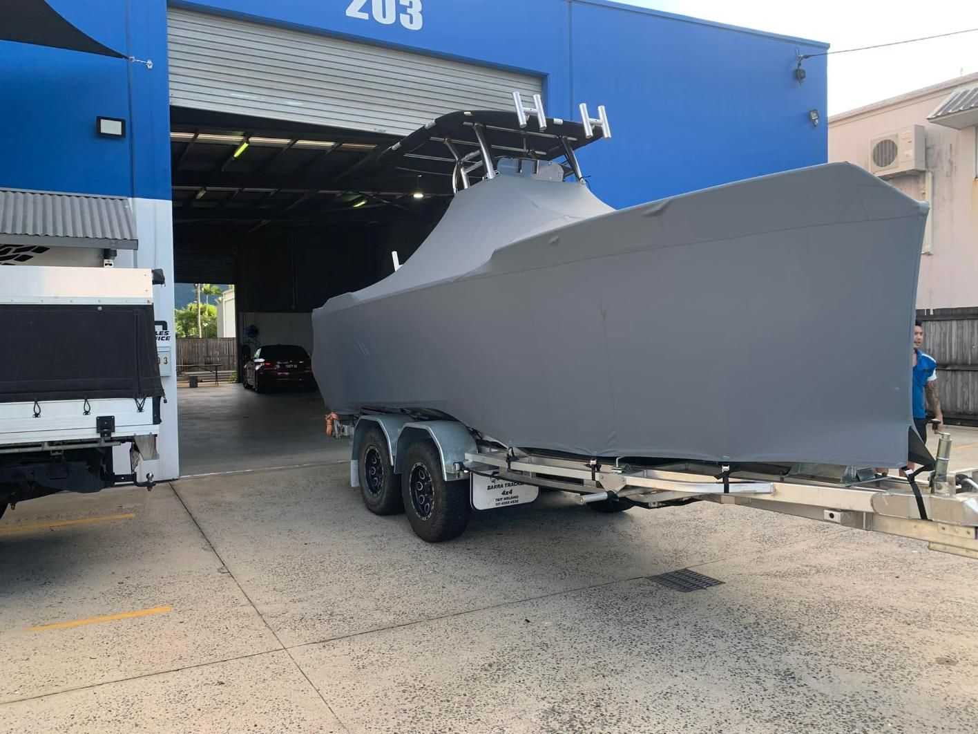 Boat with Cover Sitting On A Trailer In Front Of A Building — Cairns Vinyl & Canvas in Bungalow, QLD
