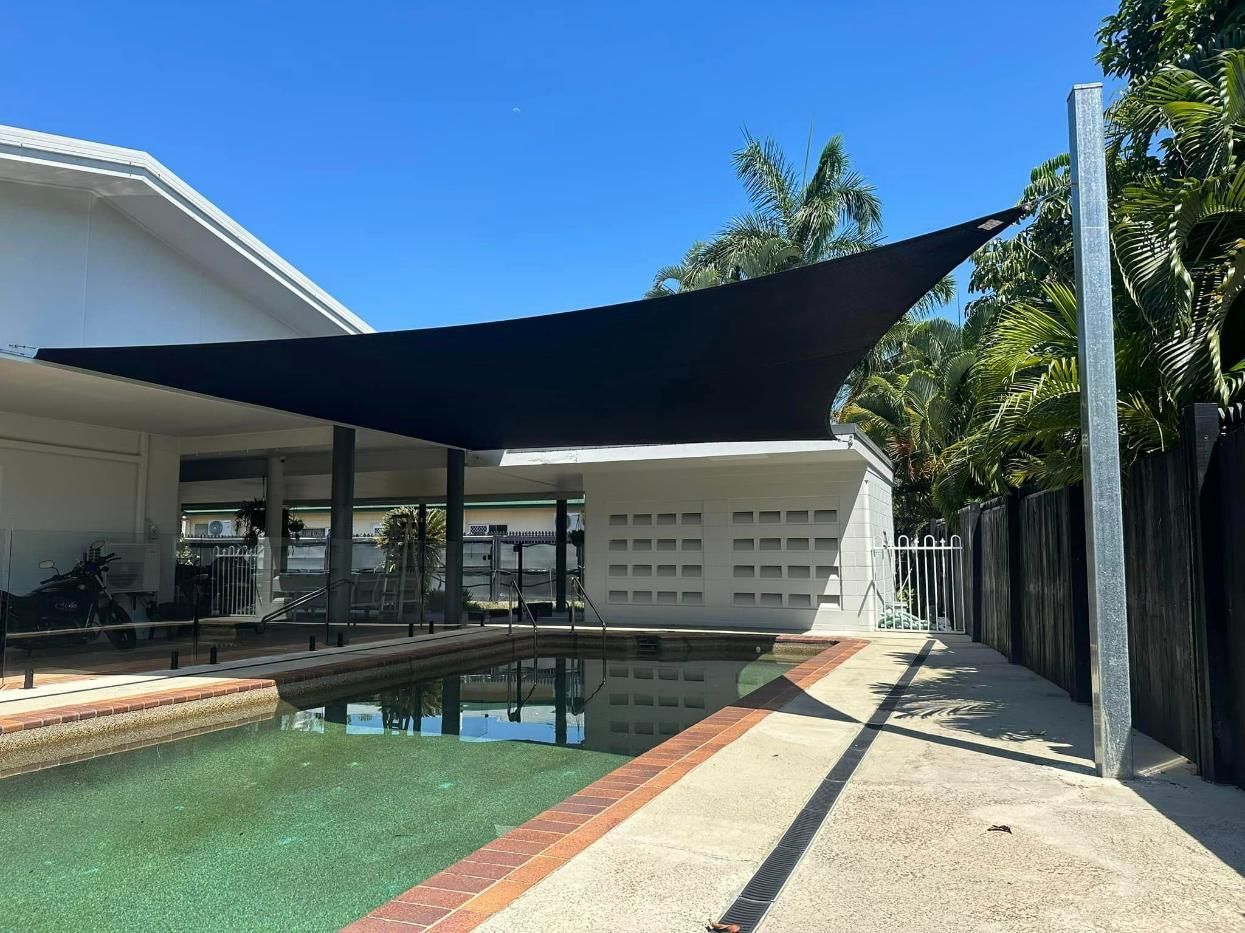 Black Shade Sail Is Covering a Swimming Pool in Front of A House — Cairns Vinyl & Canvas in Bungalow, QLD