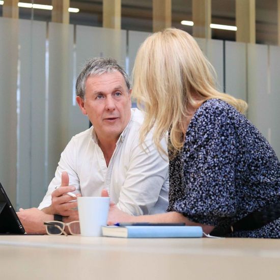 A man and a woman are sitting at a table talking to each other.