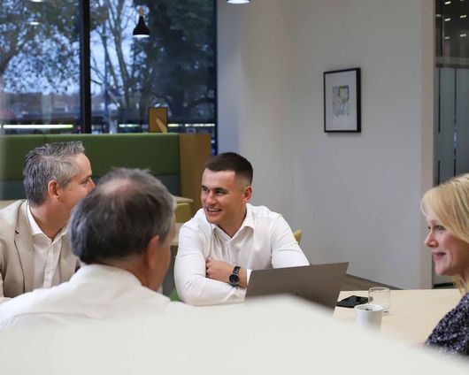 A group of people are sitting around a table talking to each other.