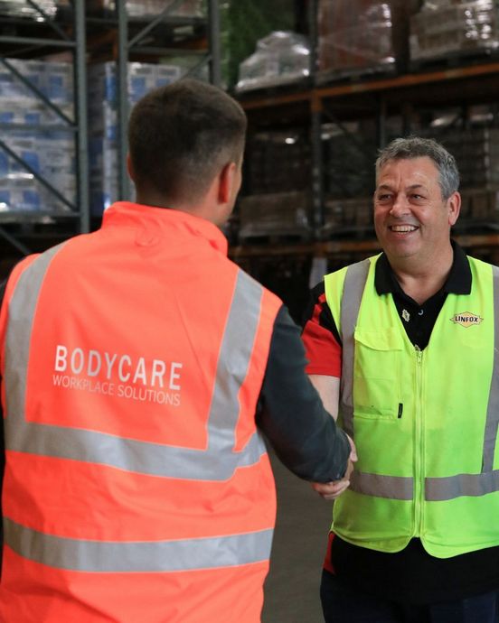 A man wearing a bodycare vest shakes hands with another man