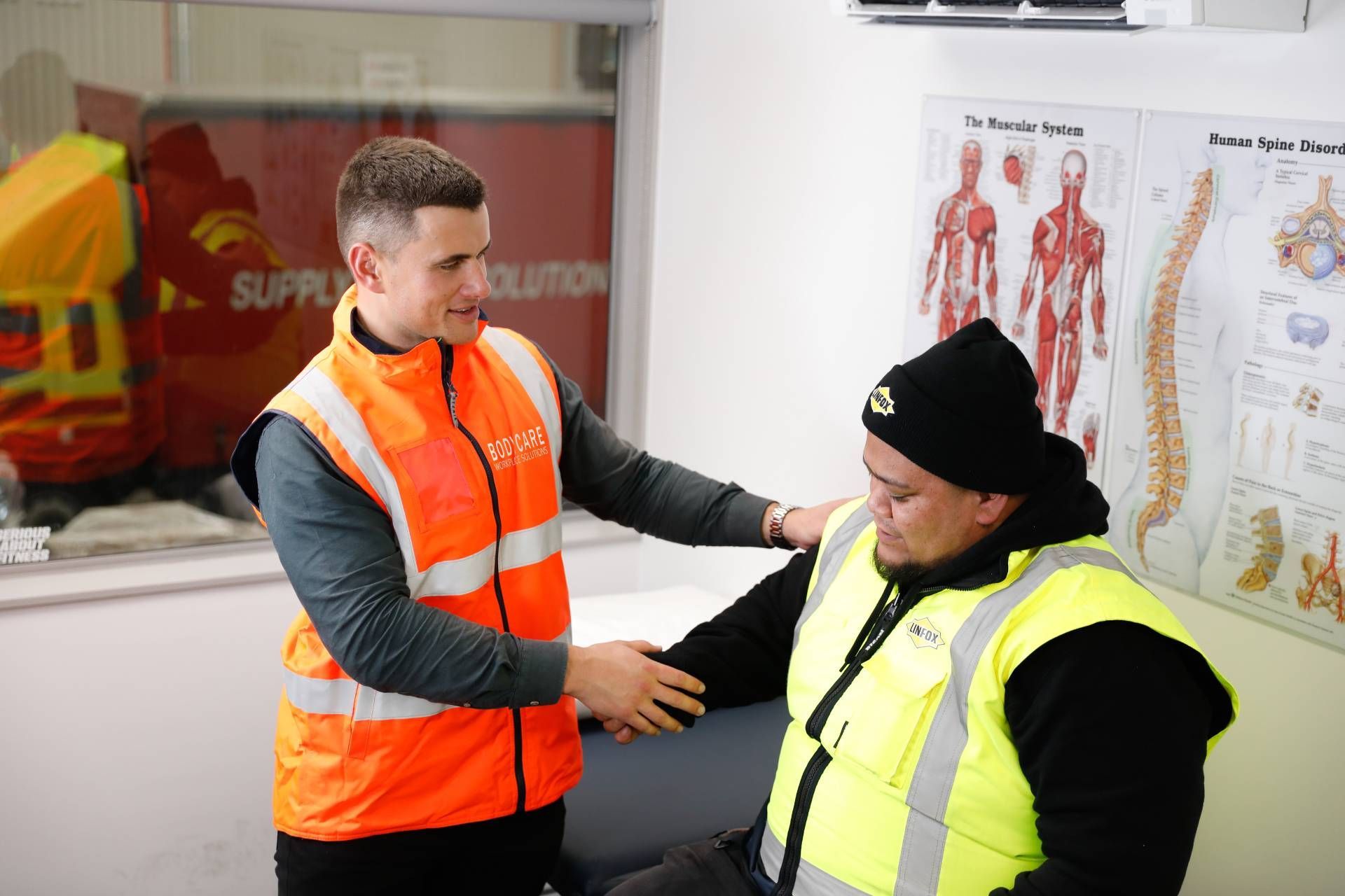 Bodycare NZ in orange vest is helping another client in a yellow vest.