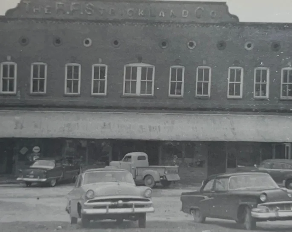 A black and white photo of cars parked in front of a building.