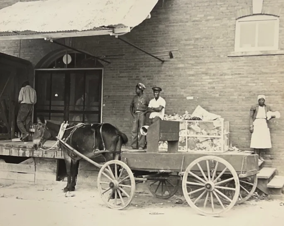 A black and white photo of a horse drawn wagon