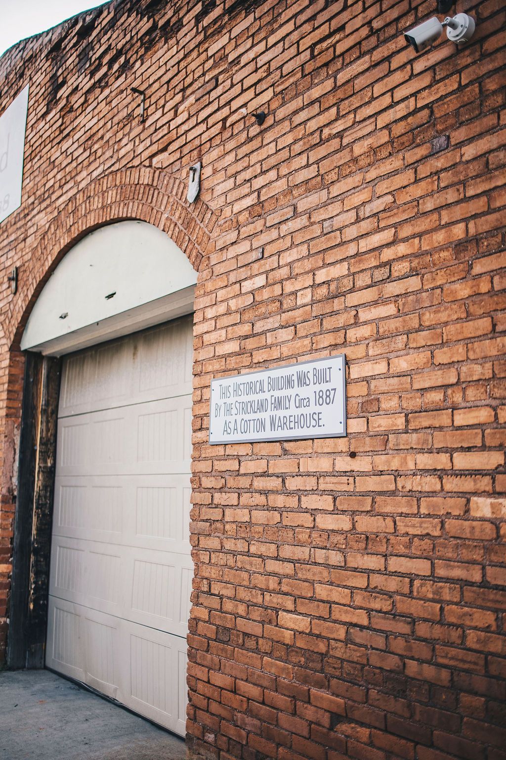 A brick building with a white garage door and a sign on it.