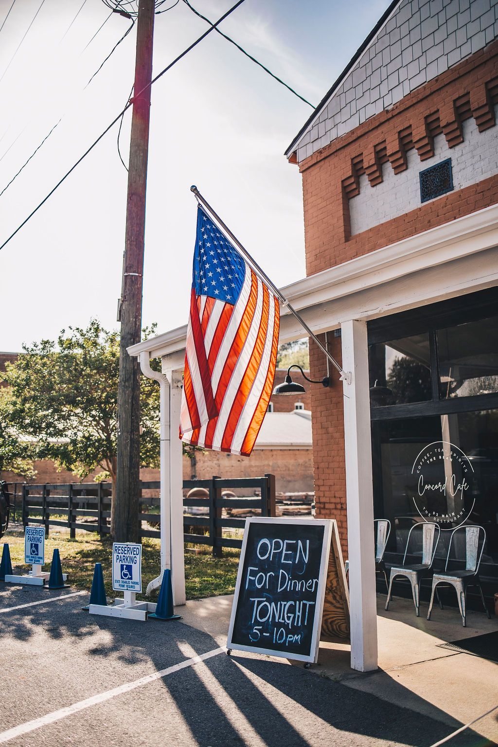 An american flag is flying in front of a building with a sign that says open for drinks tonight.