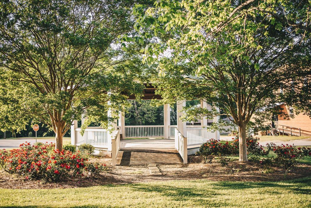 There is a gazebo in the middle of a park surrounded by trees.