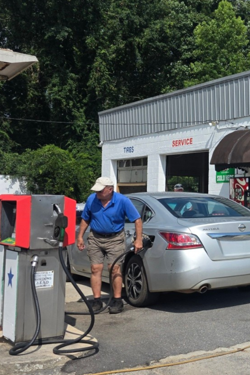 A man is pumping gas into a car at a gas station