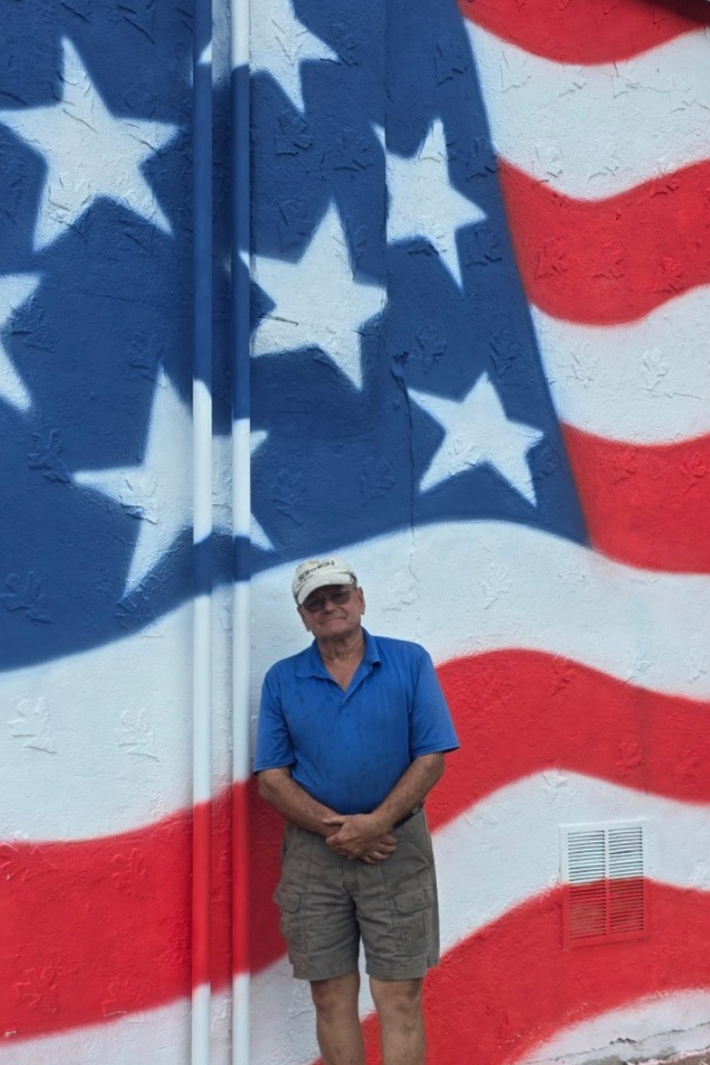 Mr. Chris Lee in standing in front of the mural