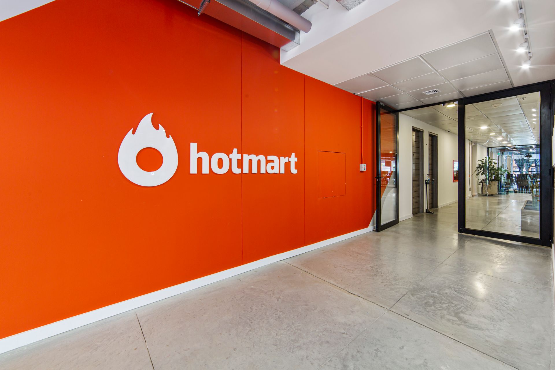 Una gran pared naranja con el logotipo de Hotmart.
