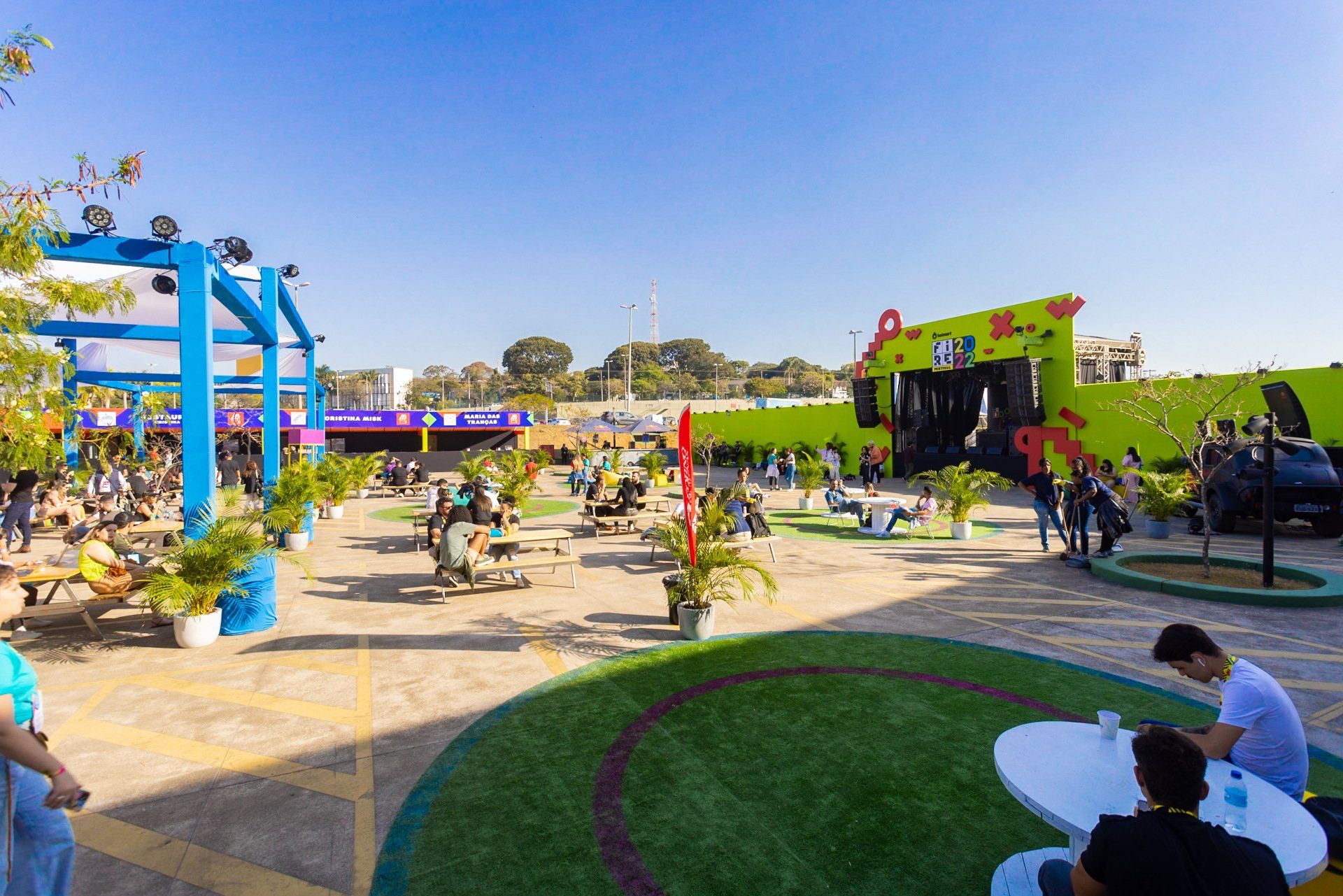 Um grupo de pessoas está sentado em mesas em um parque.