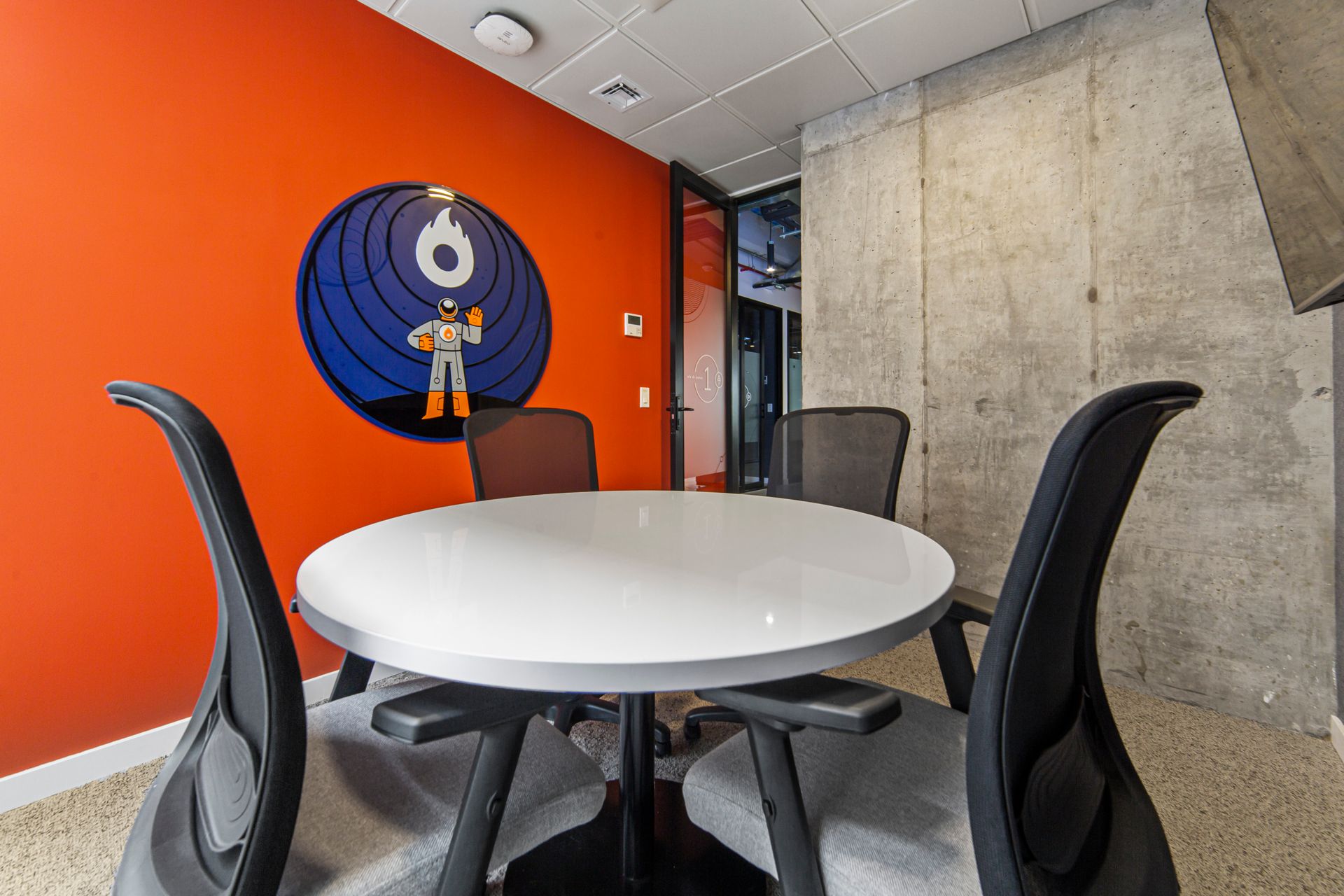 Una sala de reuniones con una mesa redonda y sillas y un cuadro en la pared.