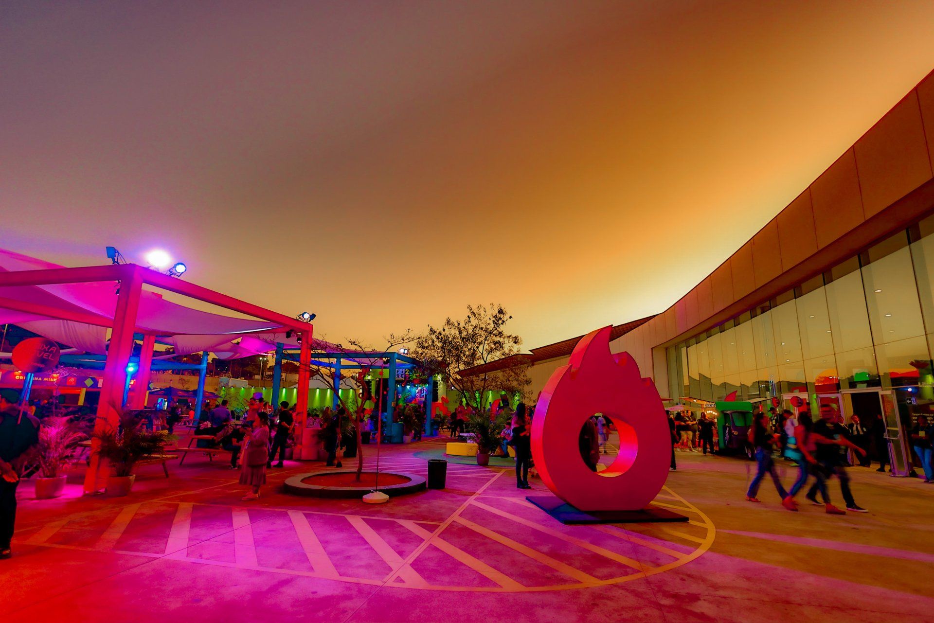 Um grupo de pessoas está caminhando ao redor de uma grande escultura rosa.