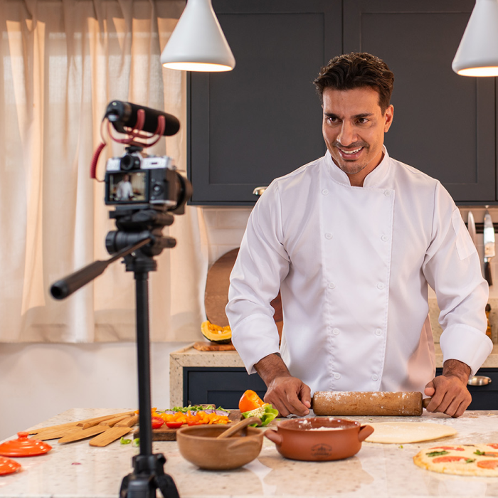 Un hombre con uniforme de chef extiende masa frente a una cámara.