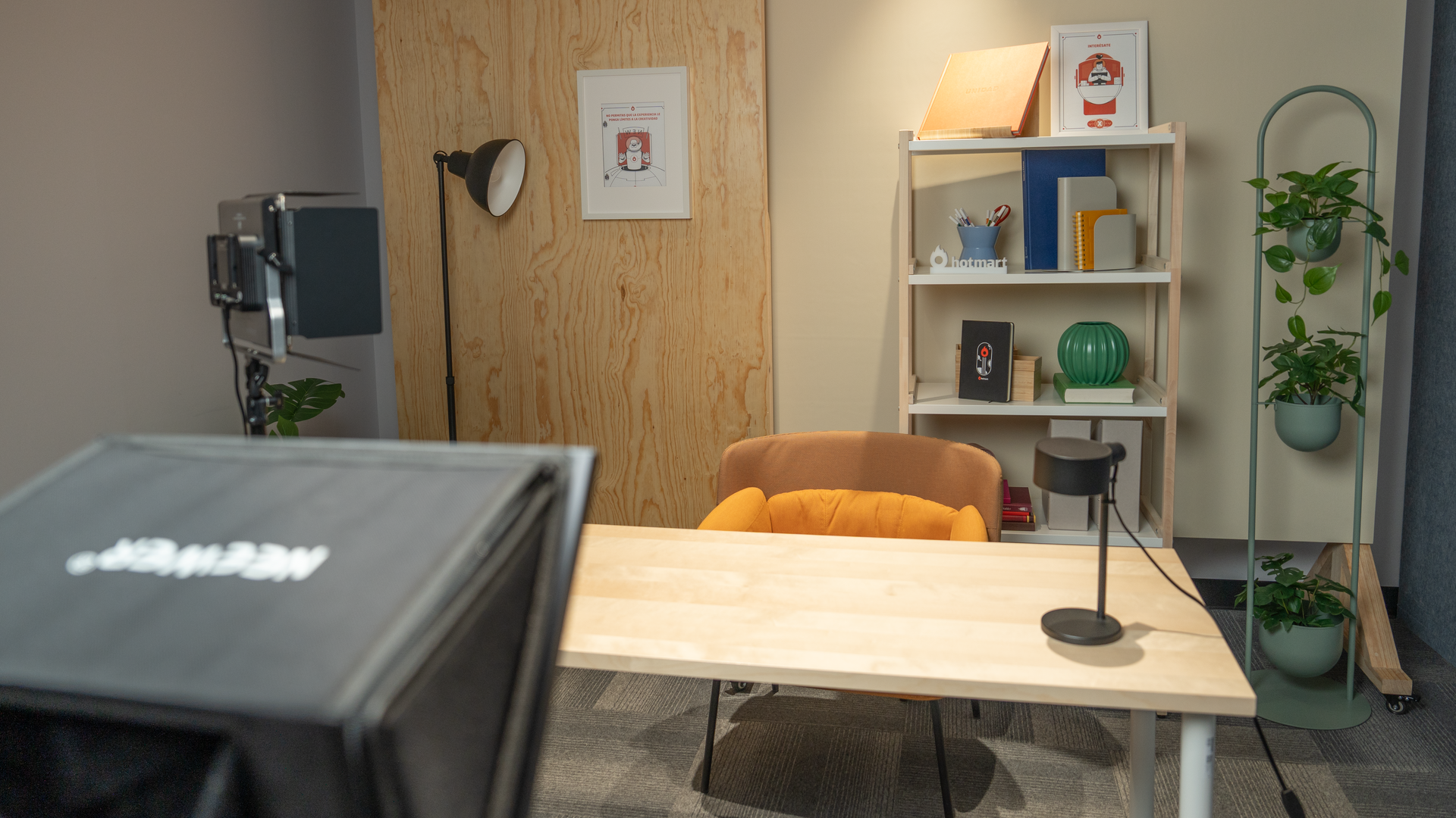 Una habitación con un escritorio, una silla, una estantería, una lámpara y un proyector.