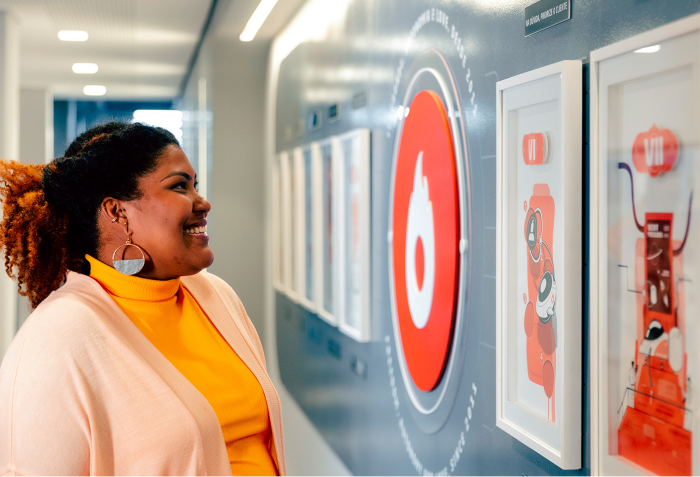 A woman is looking at a painting on a wall.