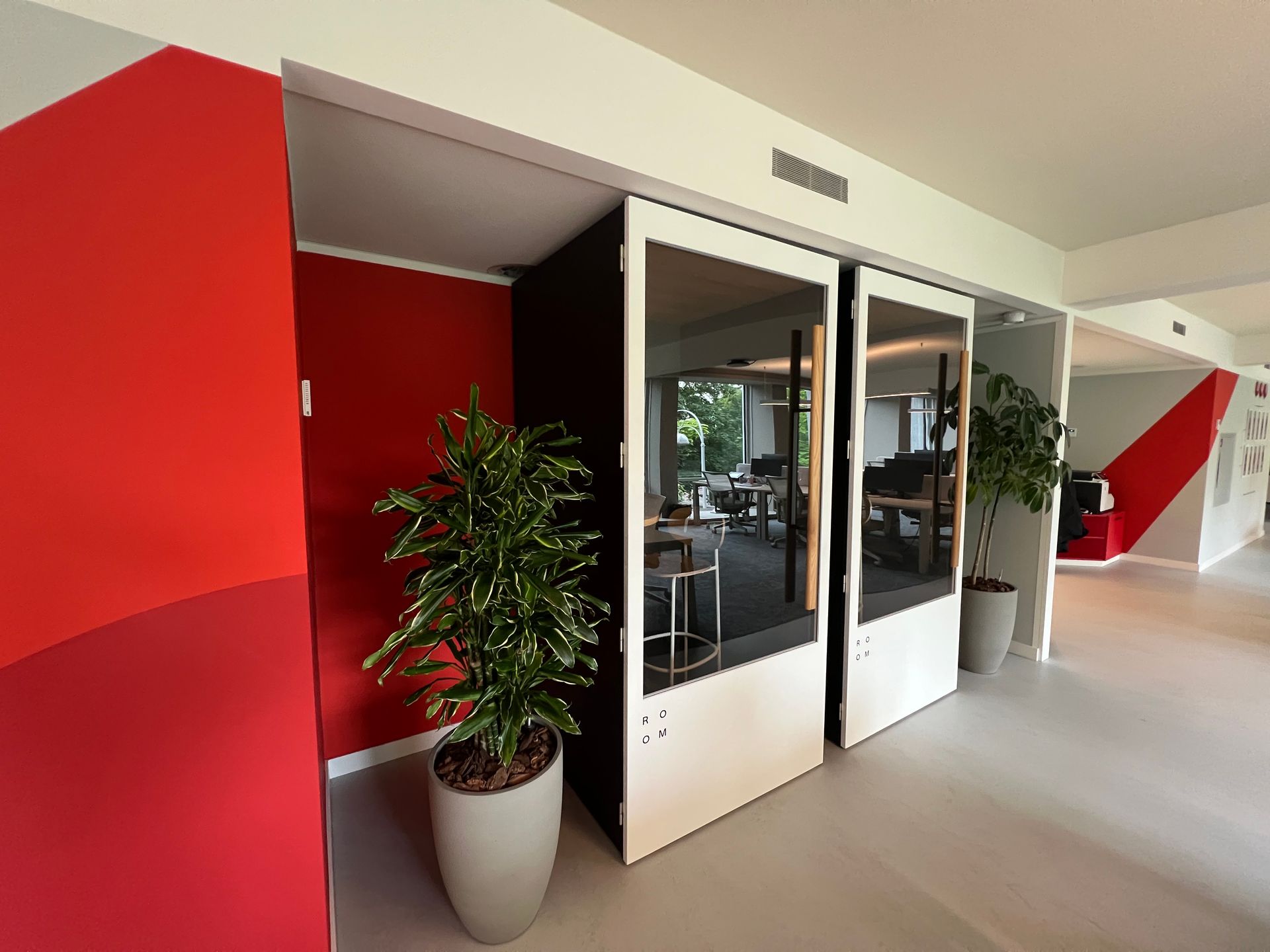 Una habitación con paredes rojas, puertas blancas y plantas en macetas.