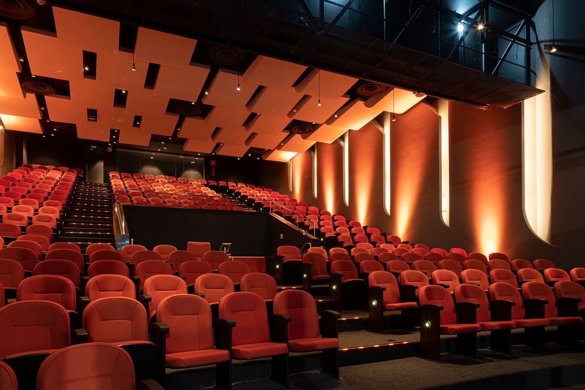 Un auditorio vacío con asientos rojos y escaleras.