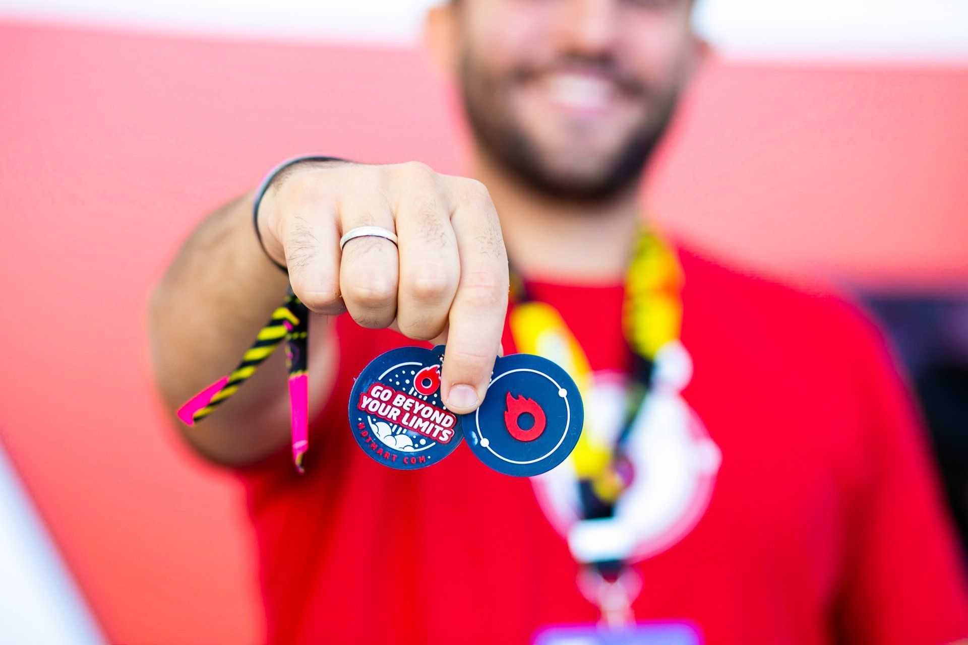Um homem de camisa vermelha segura dois distintivos na mão.