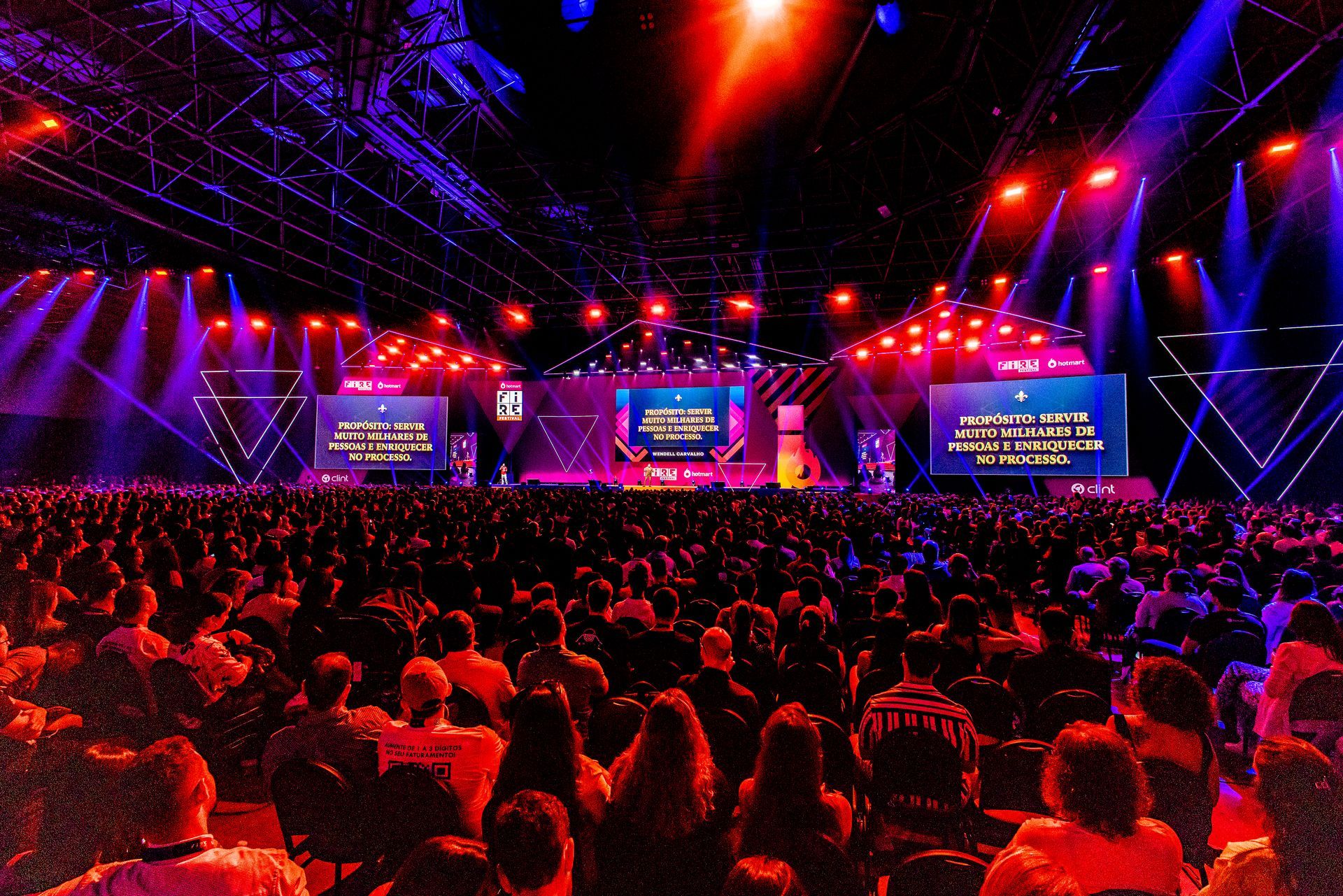Uma grande multidão de pessoas está sentada em frente ao palco em um show.
