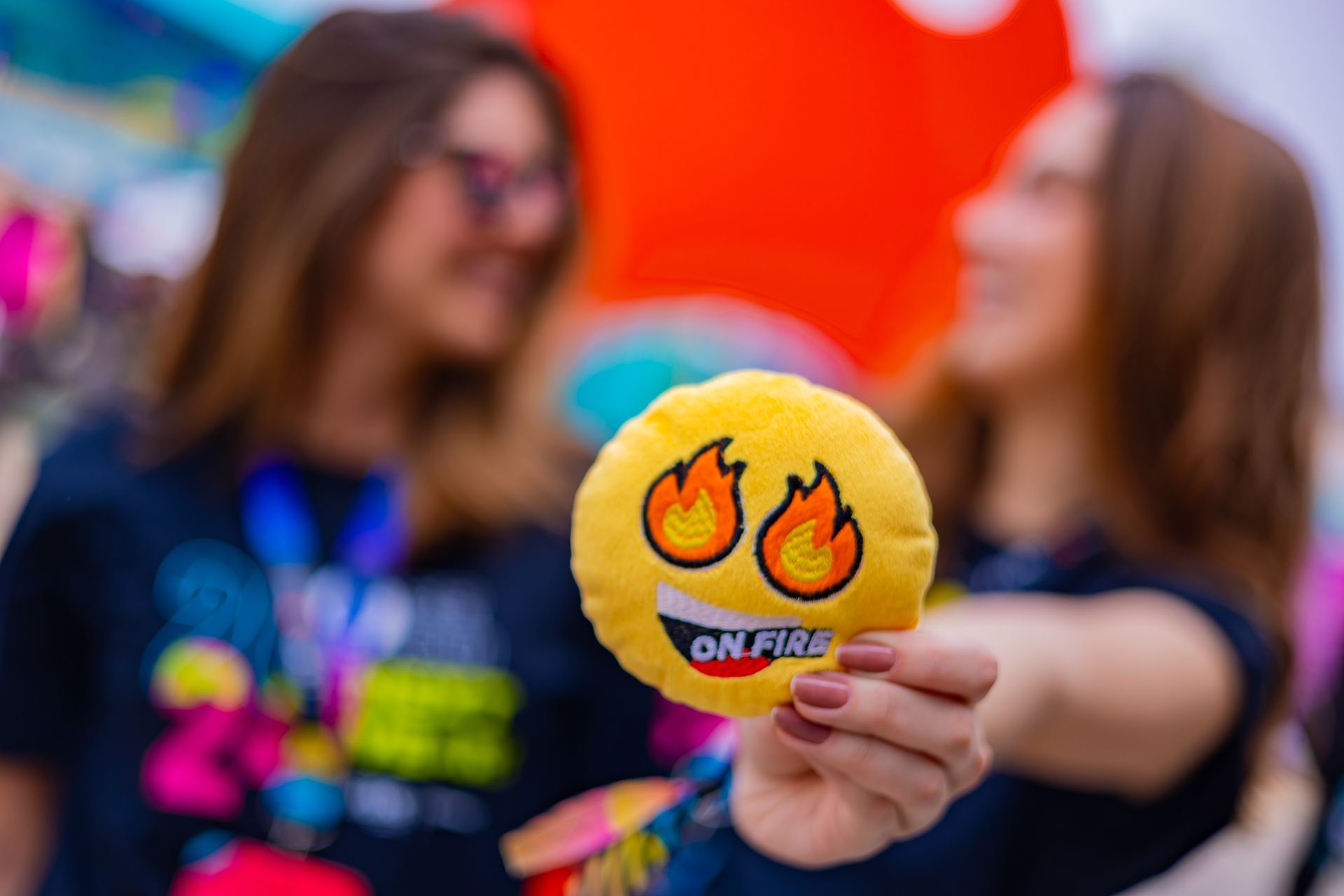 Uma mulher está segurando um rosto sorridente de pelúcia com chamas.