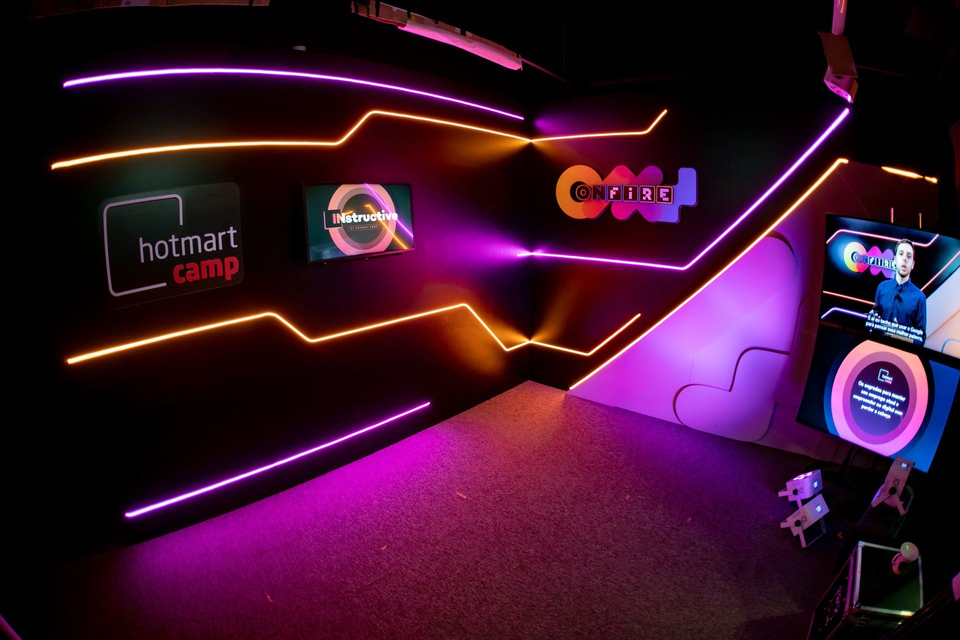 Uma sala com muitas luzes de neon e uma placa que diz hotmart camp