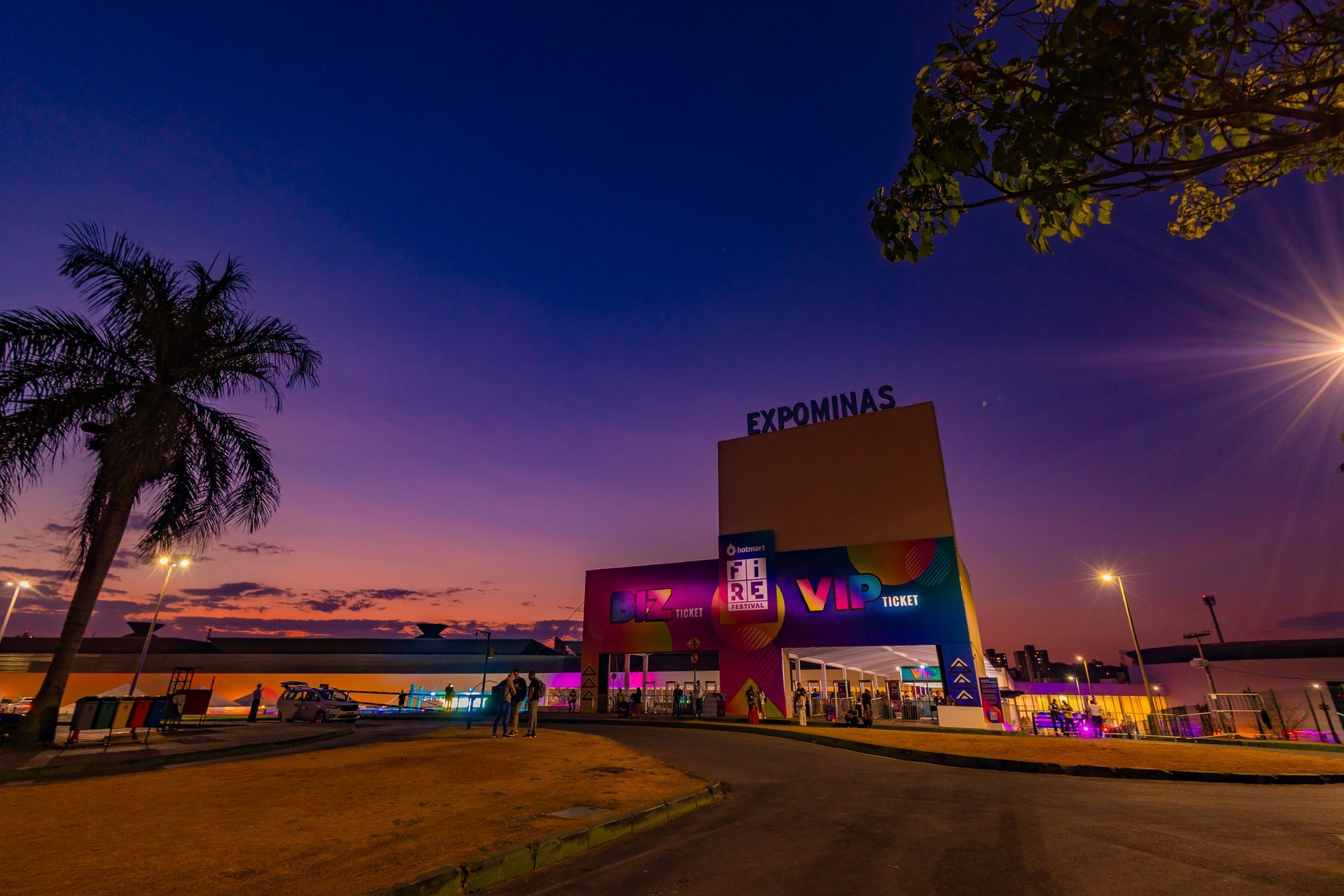 Foto do Expominas no Hotmart FIRE 2023, ao final do dia, com céu alaranjado e tons de azul e roxo. A foto mostra o foyer do Expominas com as entradas BIZ e VIP