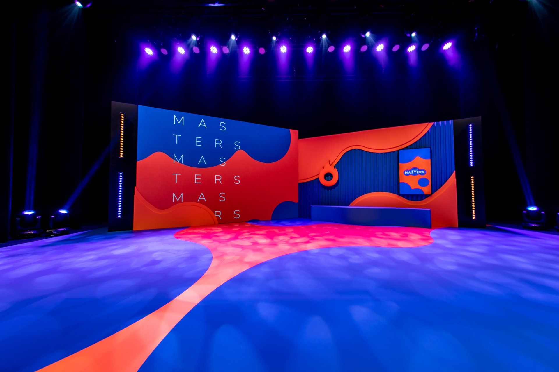 Um palco com um tapete azul e laranja e uma tela grande.