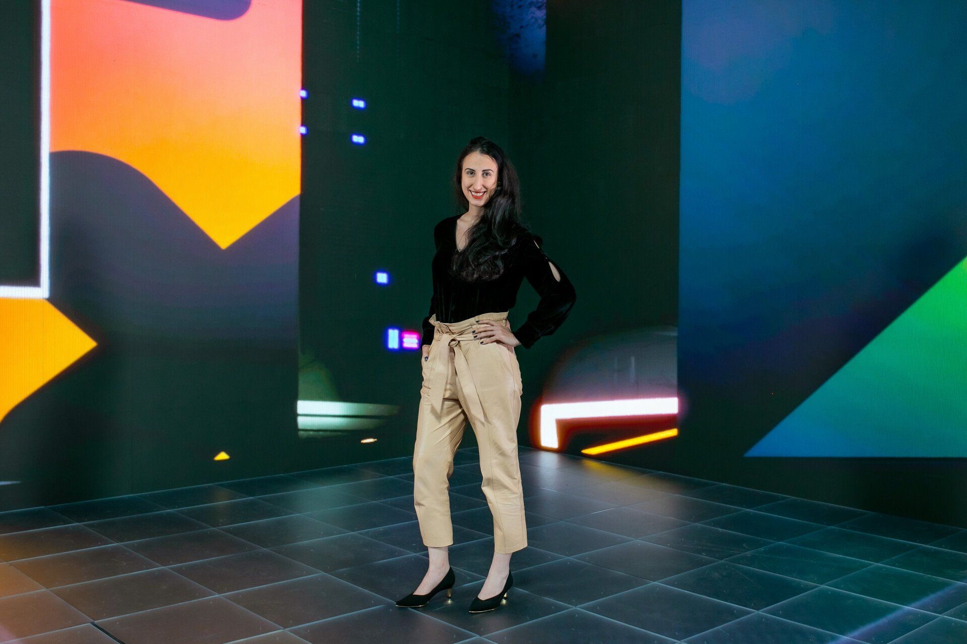 Uma mulher está parada em frente a uma tela grande em um quarto escuro.