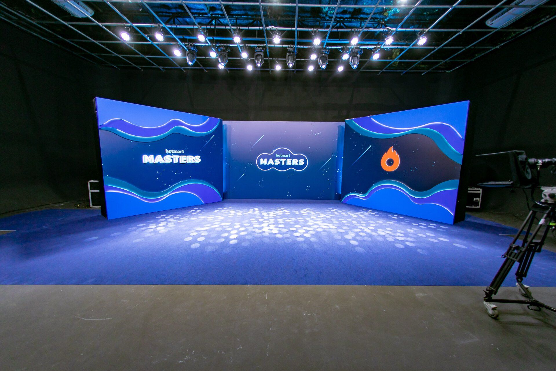 Uma sala grande com um tapete azul e uma câmera no chão.