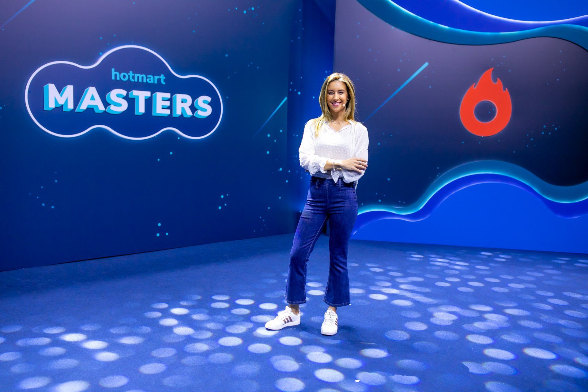 Uma mulher está parada em frente a uma placa que diz hotmart masters