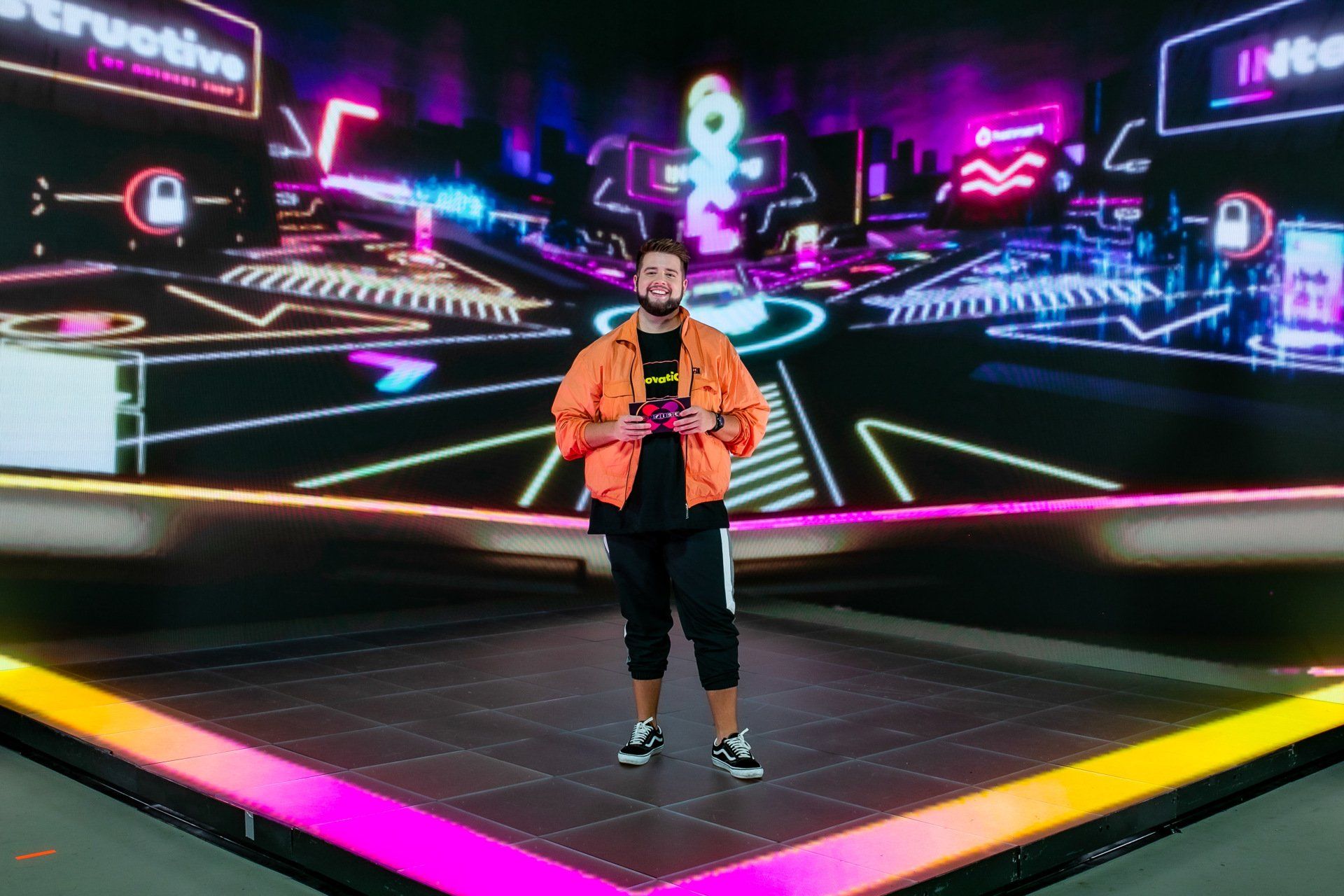 Um homem está em pé no palco em frente a uma tela grande.